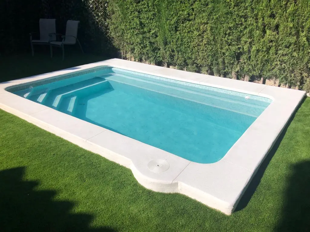 Piscina con escalera de obra junto al césped
