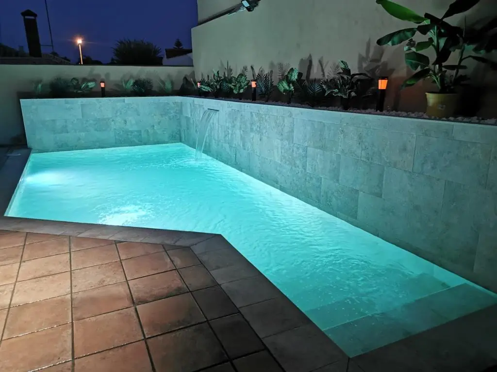 Piscina iluminada de noche con focos sumergidos